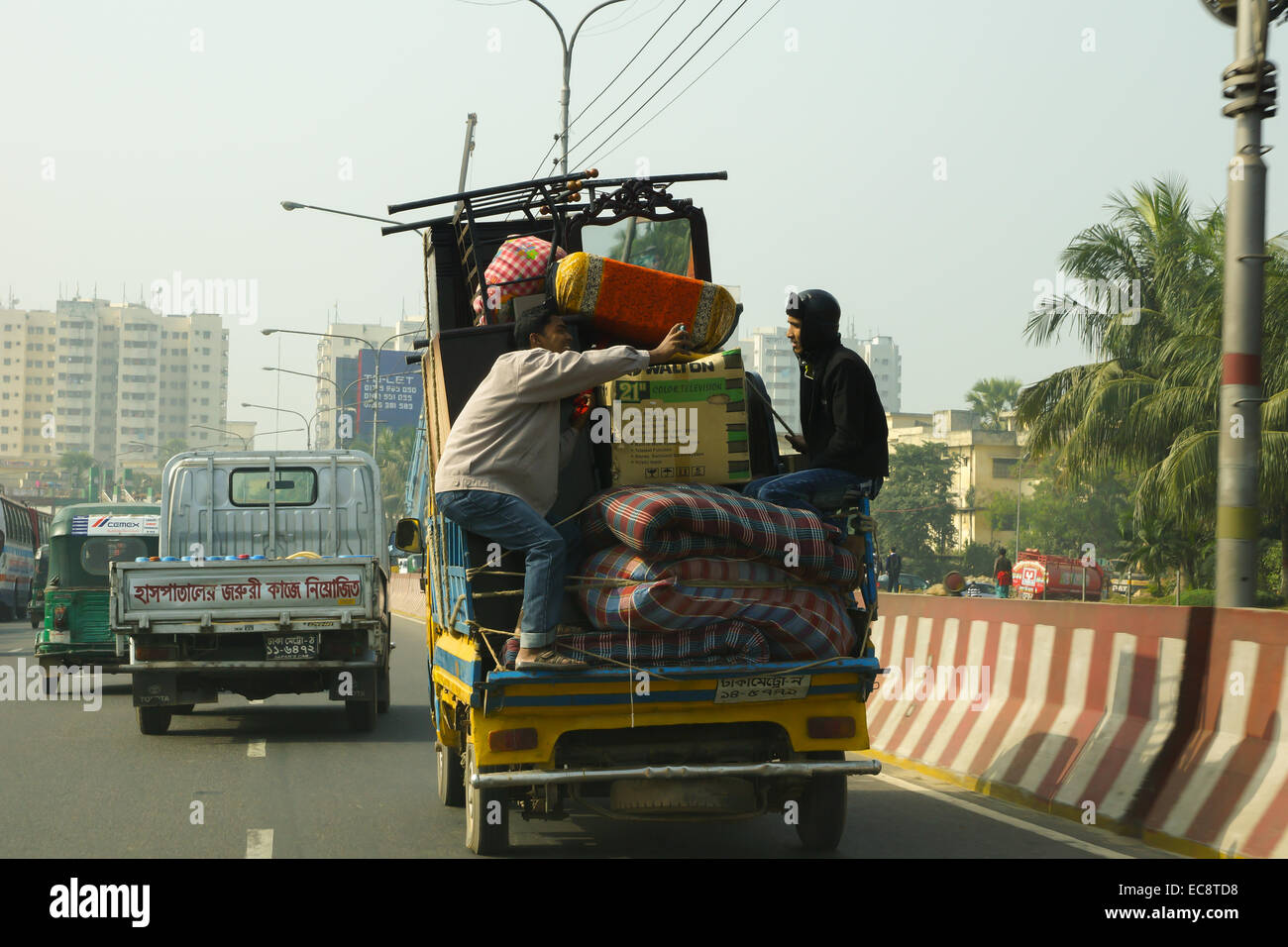 two men transporting luggage in the back of a truck, in dhaka