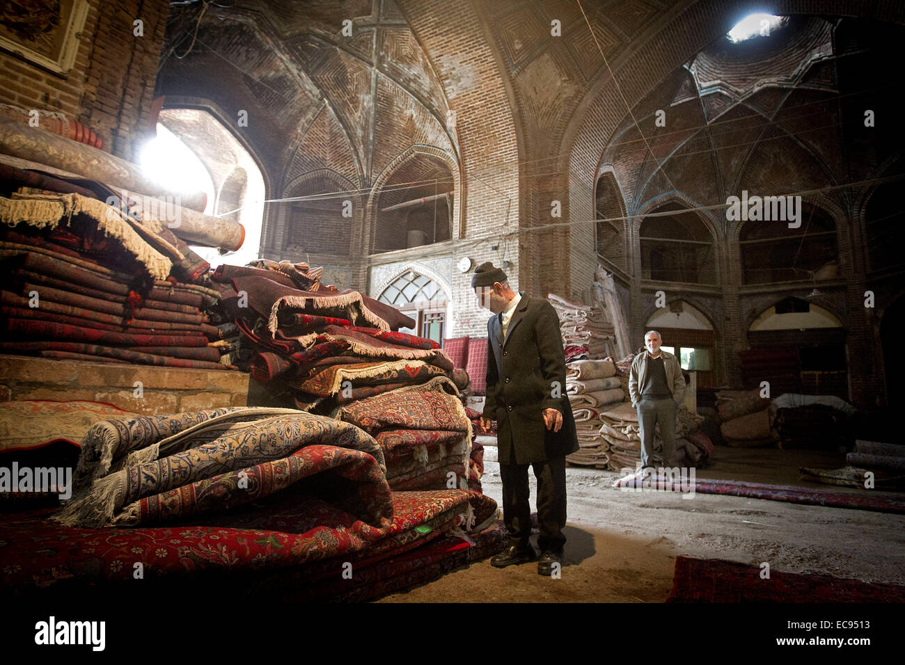 Tehran, Iran. 10th Dec, 2014. A man looks at Iranian carpets at an old bazaar in the city of Qazvin, Iran, on Dec. 10, 2014. Qazvin is an important city station of silk road. Recently the city has been elected as the host of Silk Road Forum for 2016, to be held on Aug. 30. © Ahmad Halabisaz/Xinhua/Alamy Live News Stock Photo