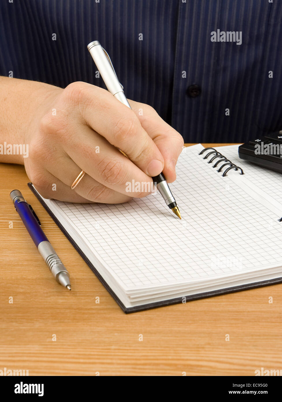 male hand writing by pen on checked notebook Stock Photo
