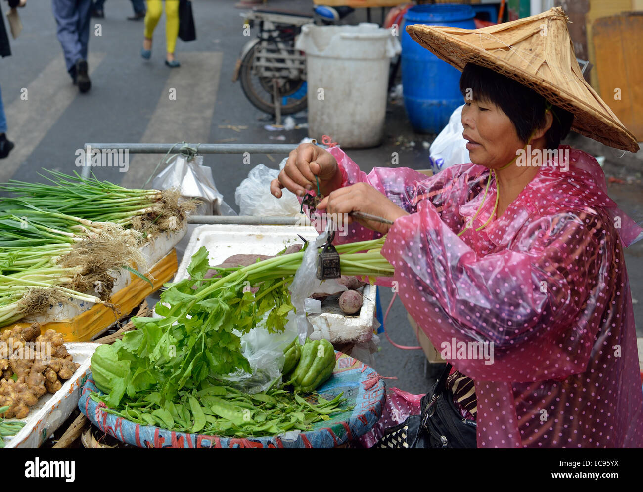 A vendor uses Chinese traditional steelyard to weigh vegetables in a street market in Xiamen, Fujian, China. 12-Nov-2014 Stock Photo