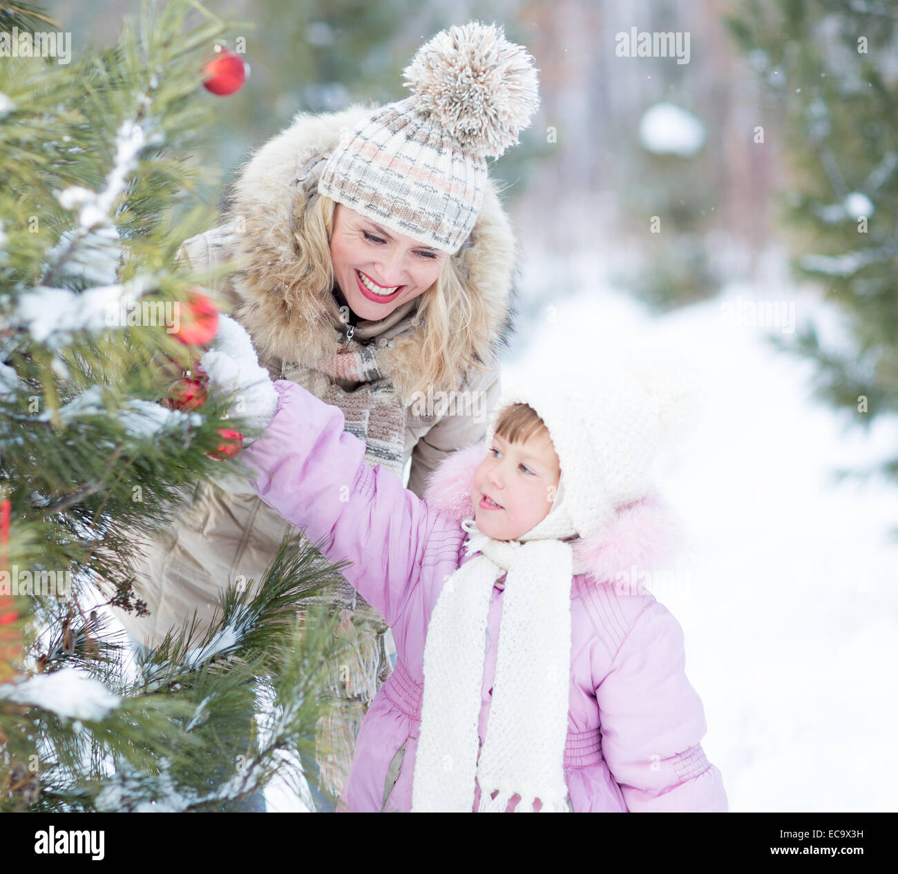 Happy family mother and child playing with christmas tree decoration outdoor Stock Photo