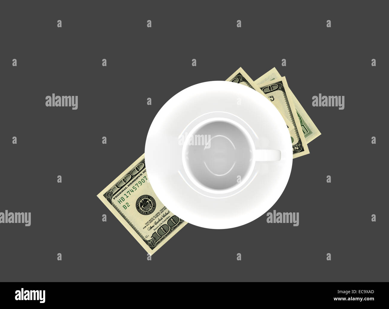 Empty white porcelain cup and saucer over United States $100 bills on dark gray background. Stock Photo