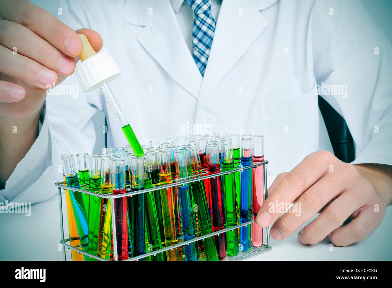 man in white coat with test tubes with liquids of different colors in a laboratory Stock Photo