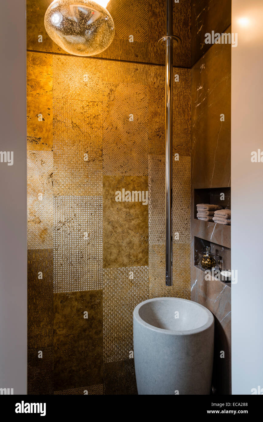 Powder room with gold ceramic tiles, granite pedestal sink and ceiling suspended faucet Stock Photo