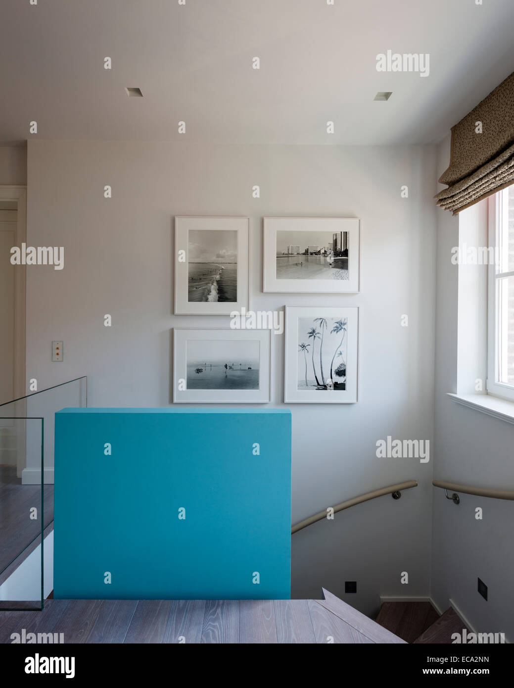 Aqua painted poured-concrete wall on landing with collection of Henry Wessel photographs Stock Photo