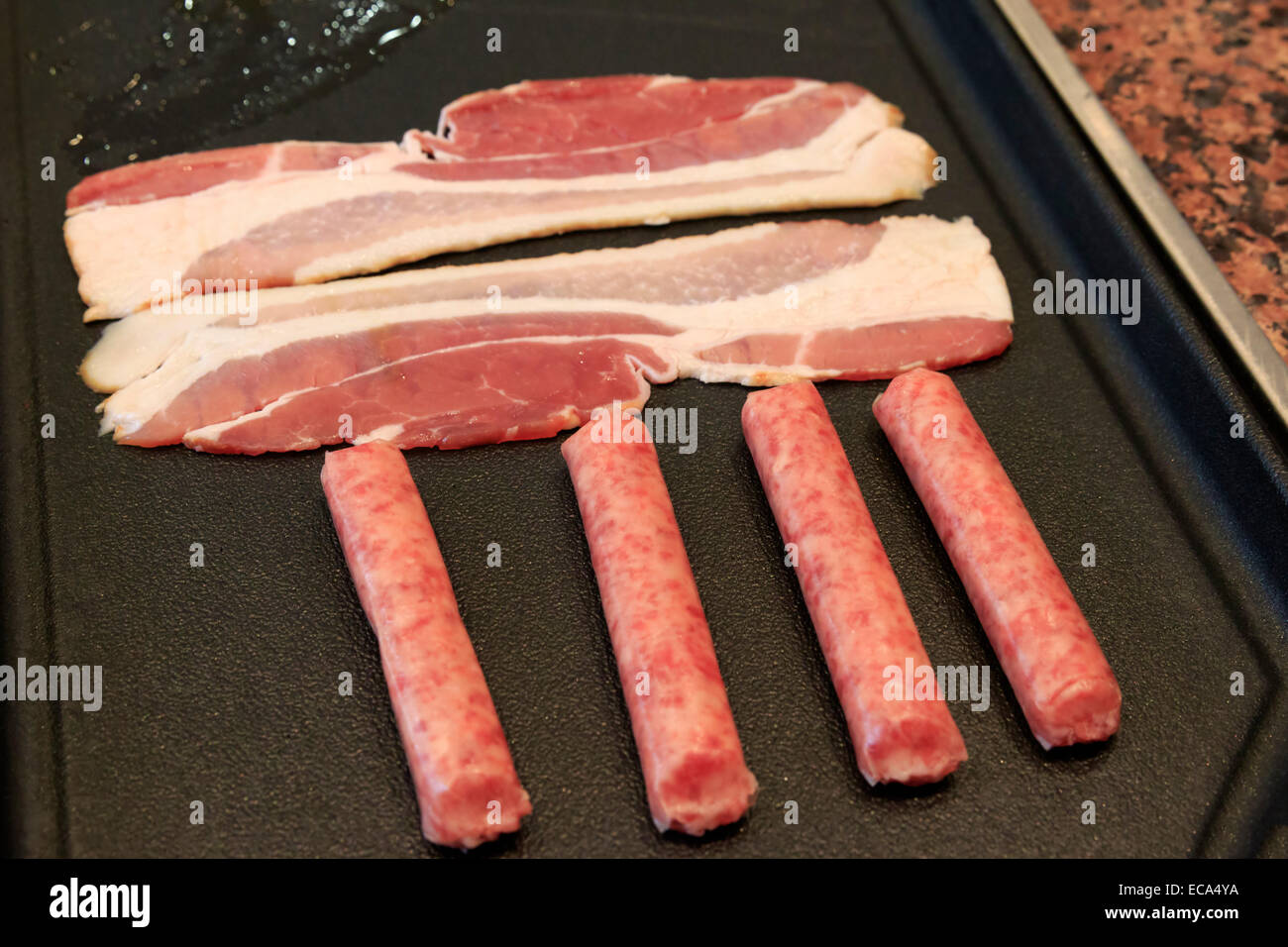 Bacon and sausage on a griddle Stock Photo