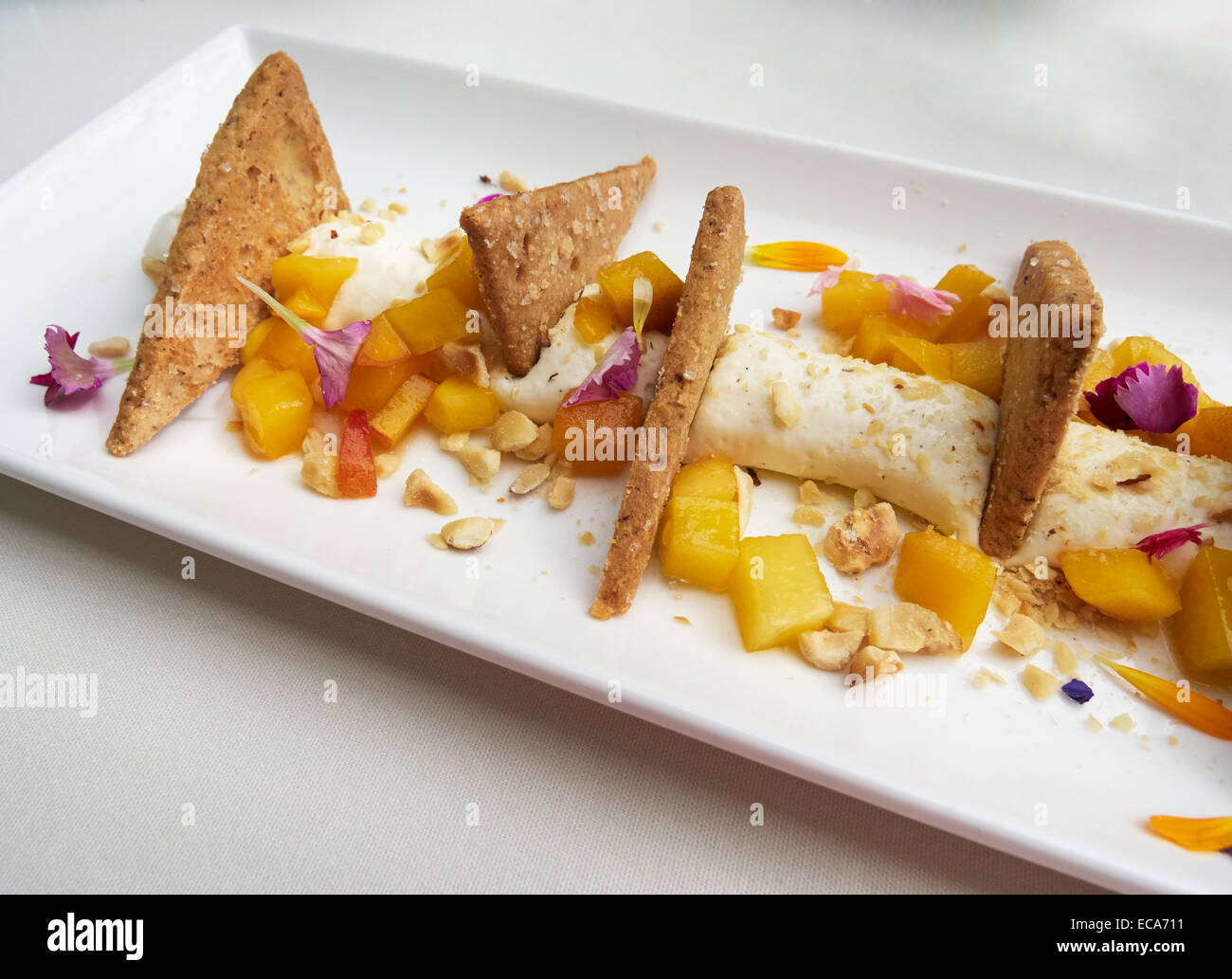 Deconstructed Cheesecake. Cream cheese with diced peaches and apricots, toasted chopped nuts, and crisp sweet biscuits Stock Photo