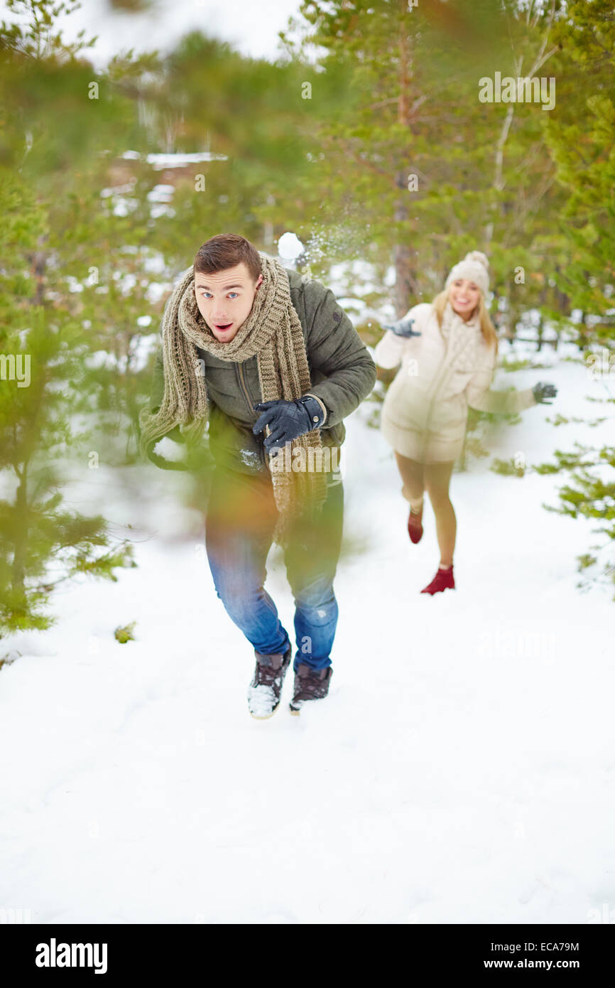 Young guy running from his girlfriend throwing snowball at him Stock ...