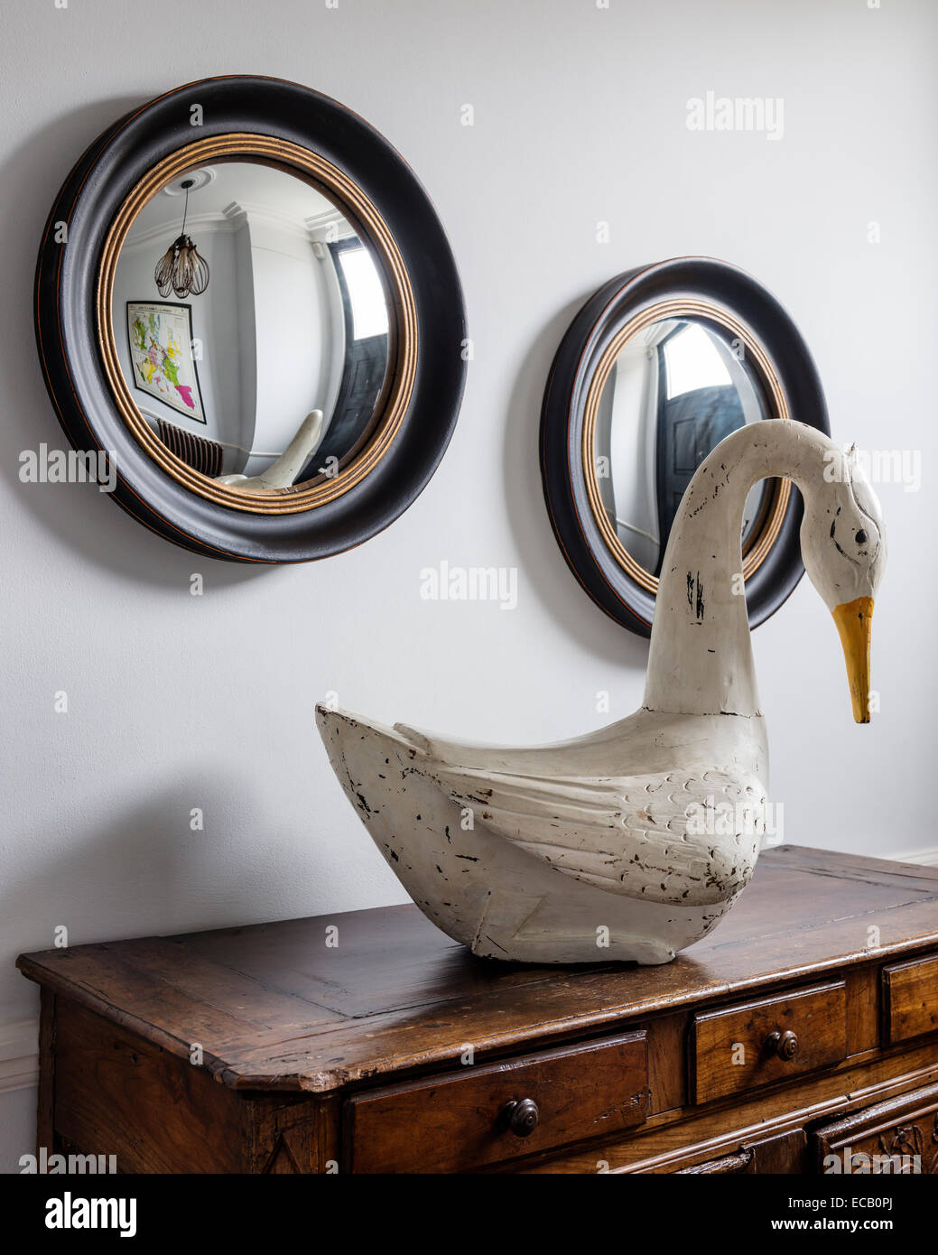 Painted wooden swan from I&JL Brown on French Provencal chest in hallway with pair of circular convex mirrors from Graham & Gree Stock Photo