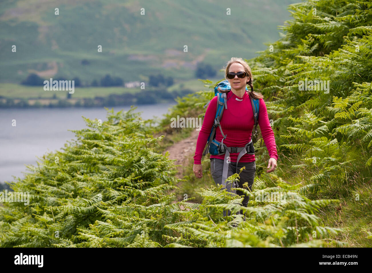 Woman 30-35 years walking with backpack, Ullswater behind, Lake District, Cumbria, England, United Kingdom Stock Photo