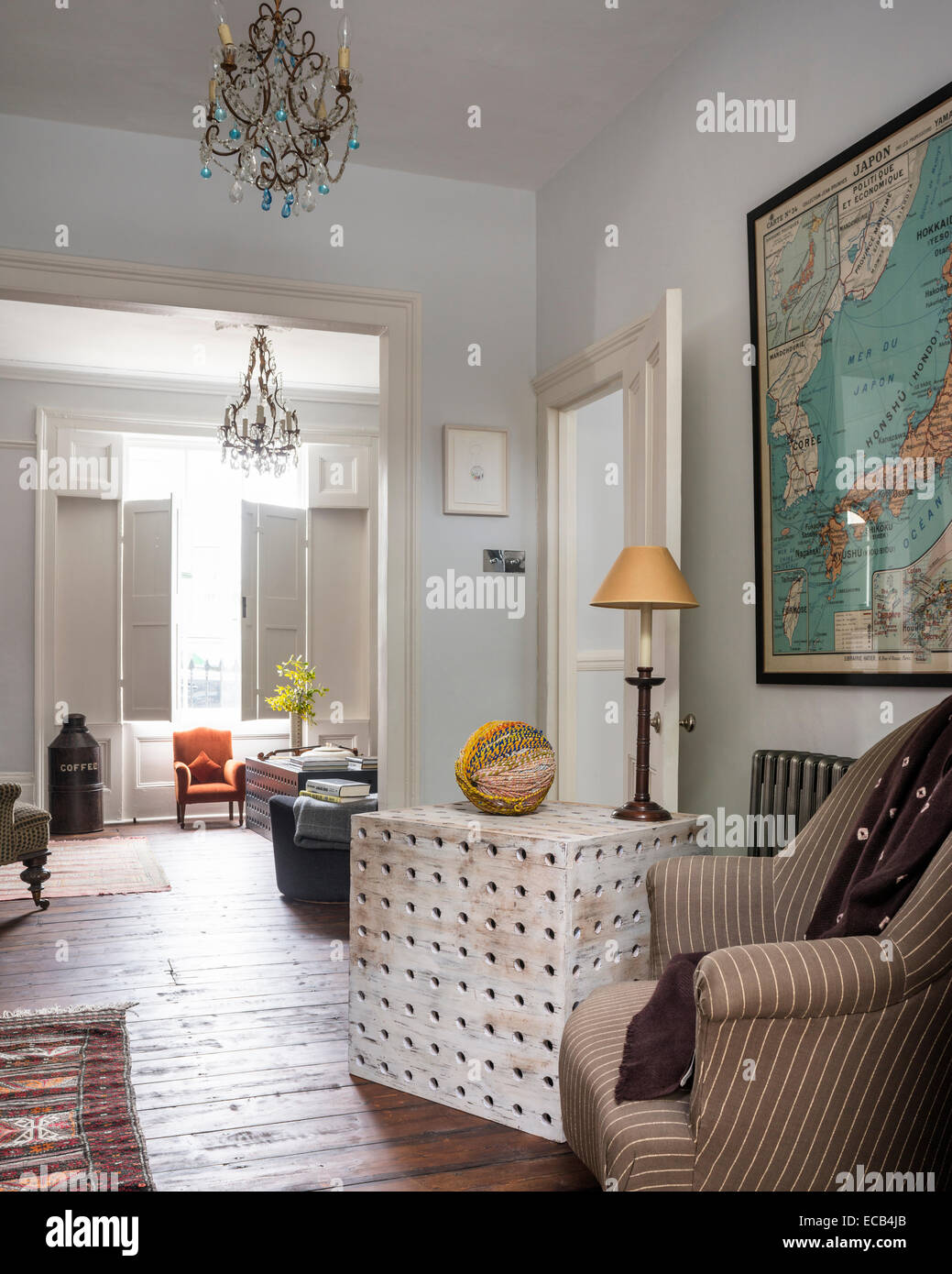 Wooden side table by Selina van der Geest in living room with wooden floors, vintage map and pair of chandeliers from Anne Fowle Stock Photo