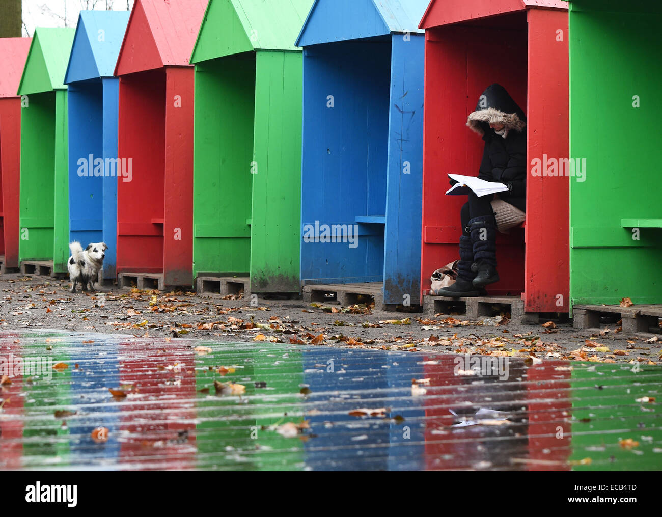 A young woman sits inside a colourful hut while it's raining at Tiergarten, Berlin, Germany, 11 December 2104. Photo: Jens Kalaene/dpa Stock Photo