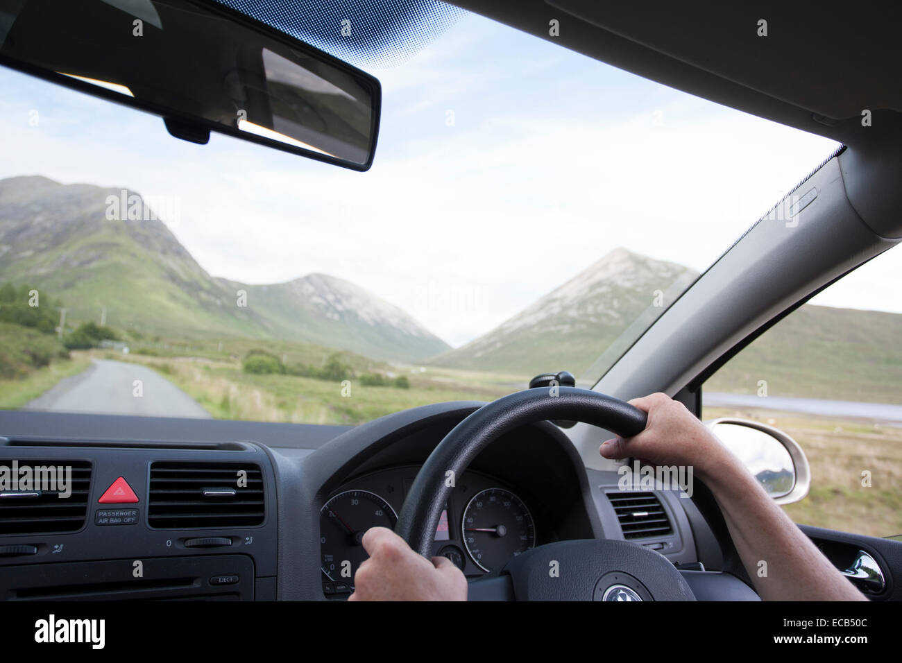 Womans hands on steering wheel in car driving by Loch Slapin, Isle of Skye, Scotland, United Kingdom Stock Photo
