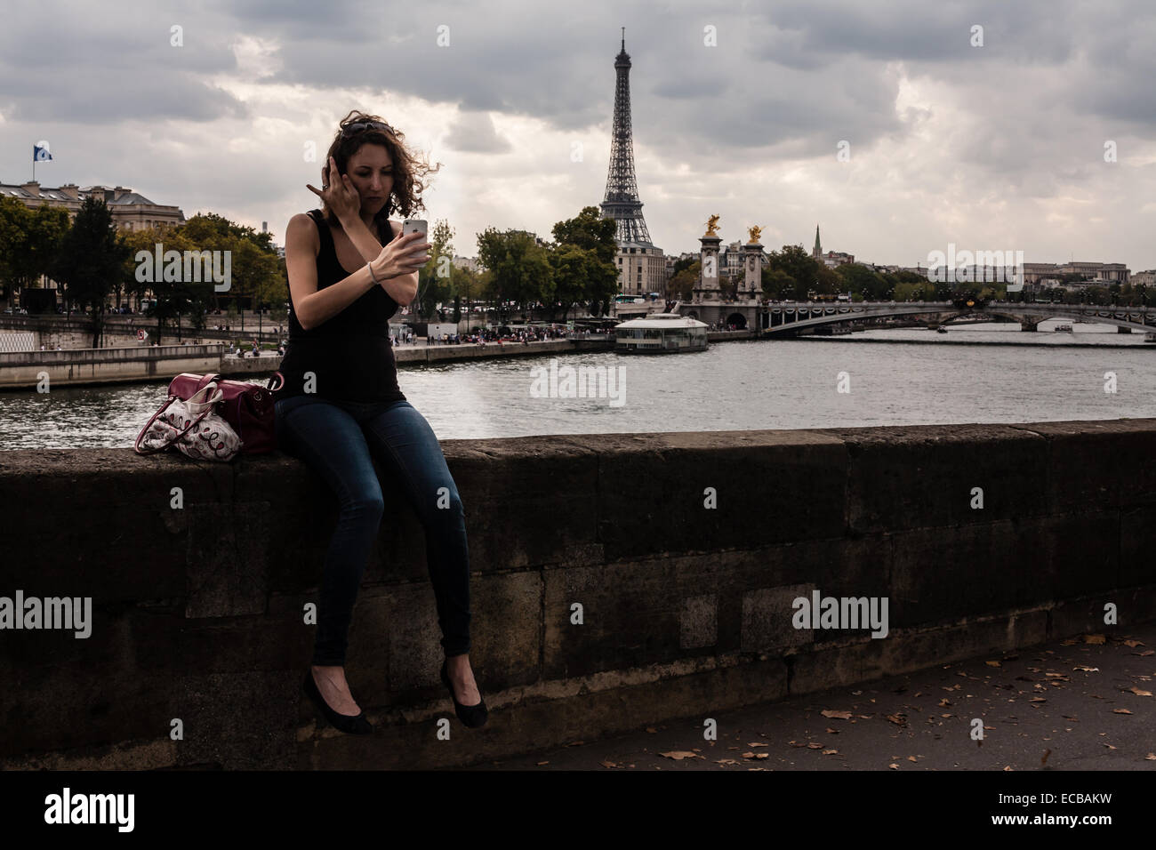 Pregnant woman alone in Paris prepares to take a selfie on a windy day