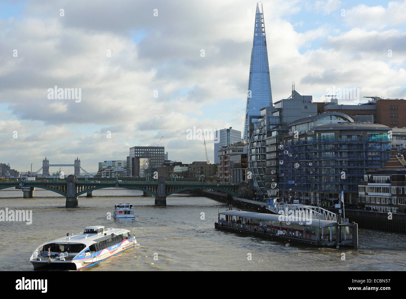 The South Bank of the River Thames in London, England. The Shard dominates the skyline while boats navigate the river. Stock Photo