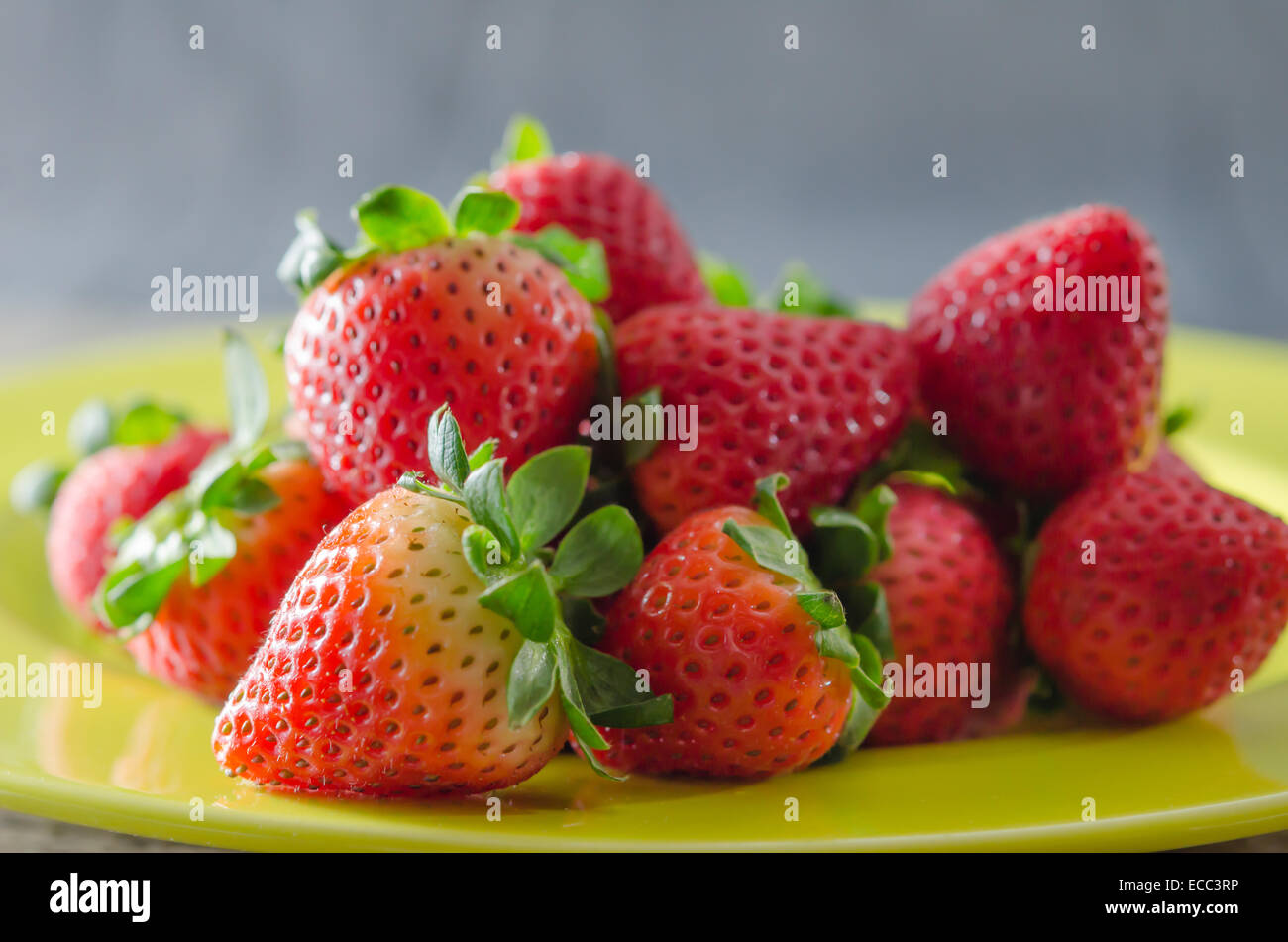 still life of fresh red strawberries on dish over wooden background ...