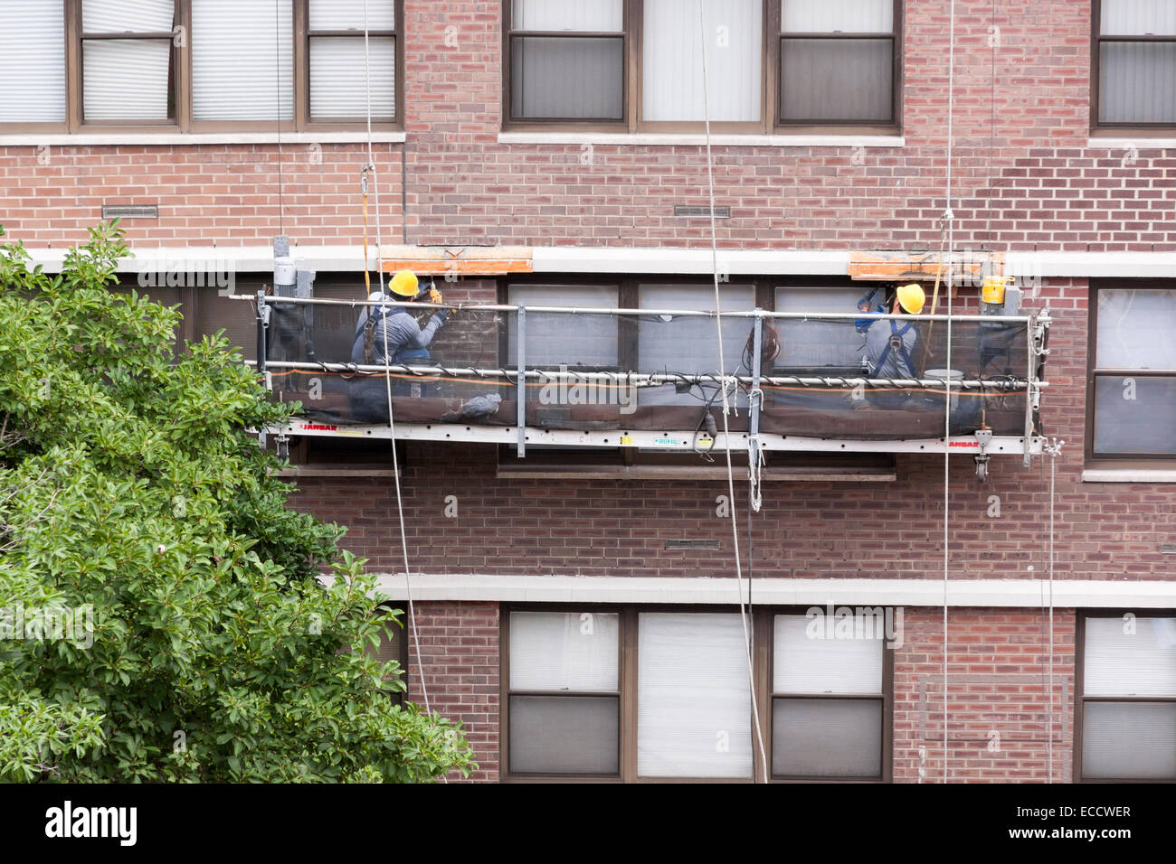 Workers repairing a high-rise apartment building lintel. Stock Photo