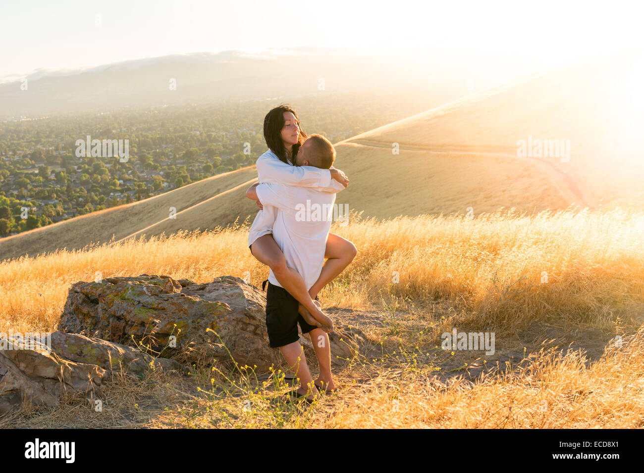 Couple embracing in sun drenched hills in California Stock Photo Alamy