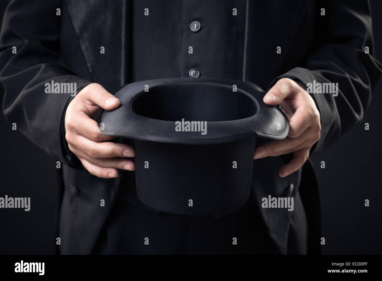 closeup of top hat in magician hands isolated on dark background Stock Photo