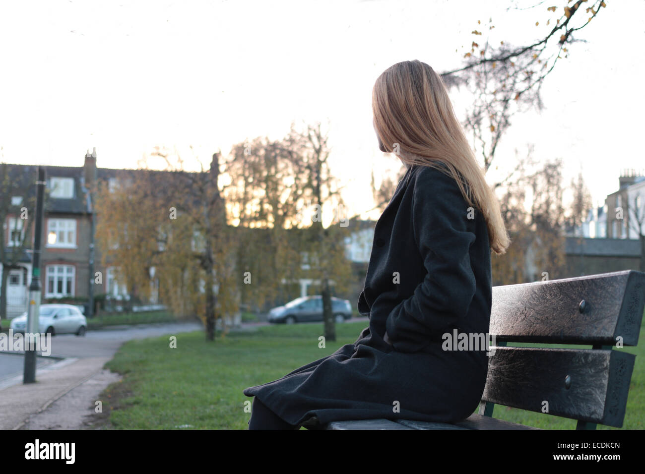Rear view shot of a young woman sitting on a seat looking away from camera. Stock Photo