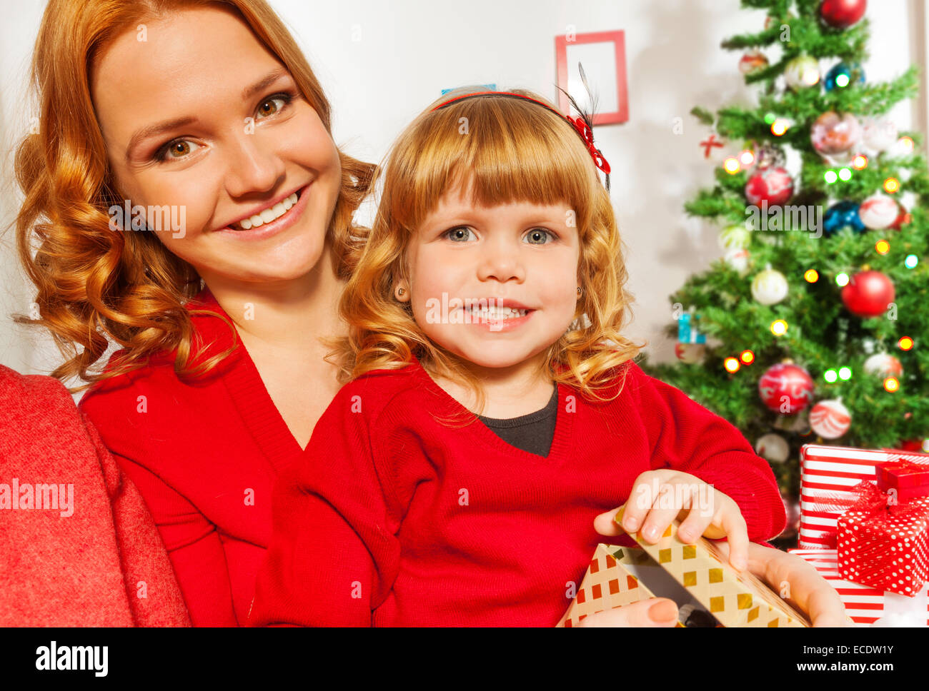 Mom and little daughter sitting by Christmas tree Stock Photo Alamy