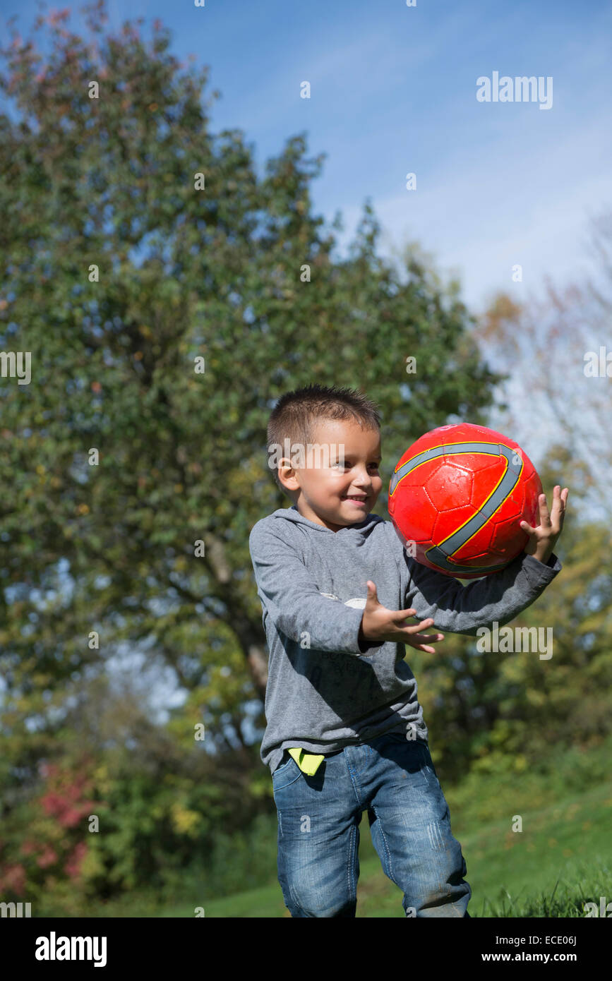 Young boy catching red football happy Stock Photo