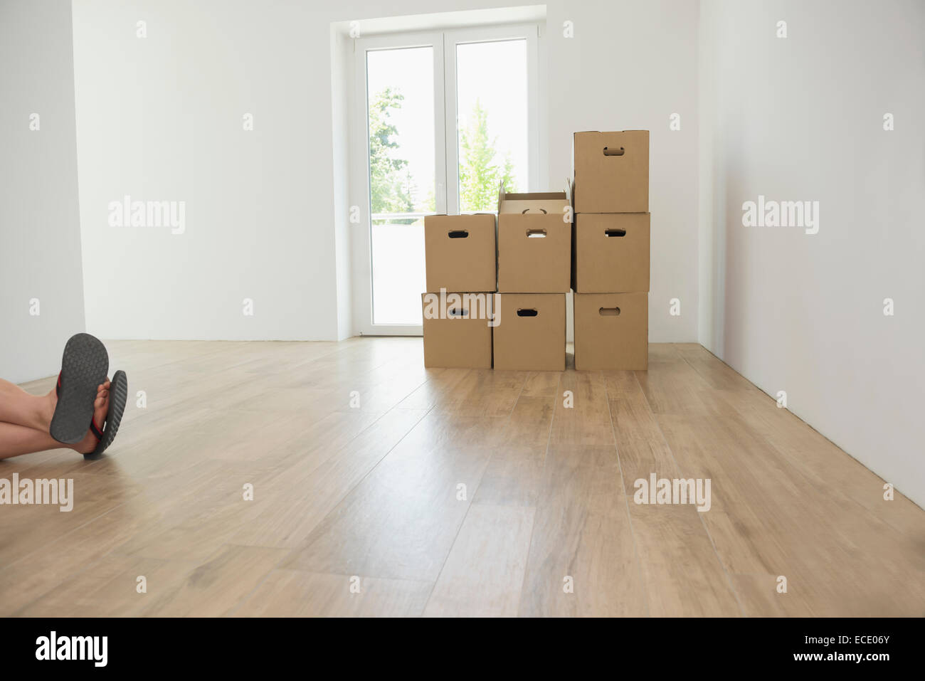 Empty room cardboard boxes wooden floor feet Stock Photo