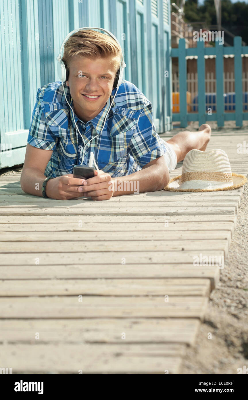 Teenager lying on front beach listening music Stock Photo - Alamy