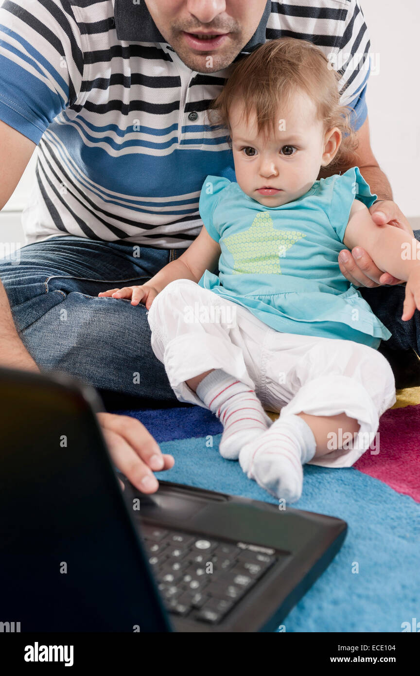 Baby father sitting carpet laptop computer Stock Photo - Alamy