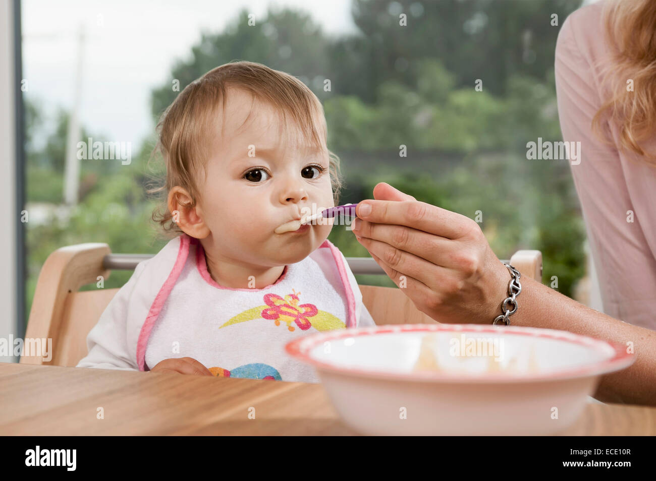 Mother feeding 1 year old baby girl eating Stock Photo