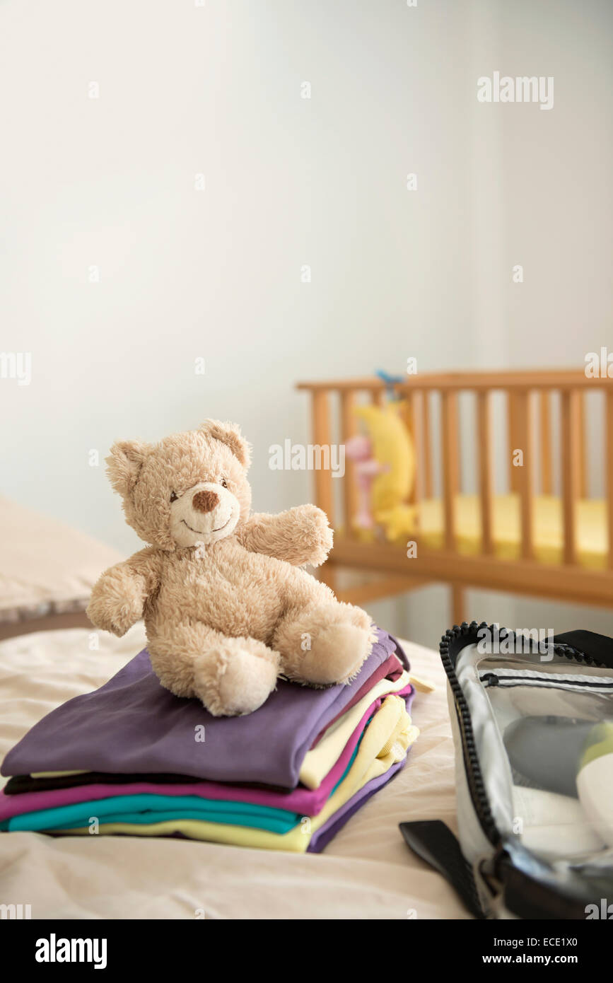 Baby bedroom cot teddy bear clothes suitcase Stock Photo