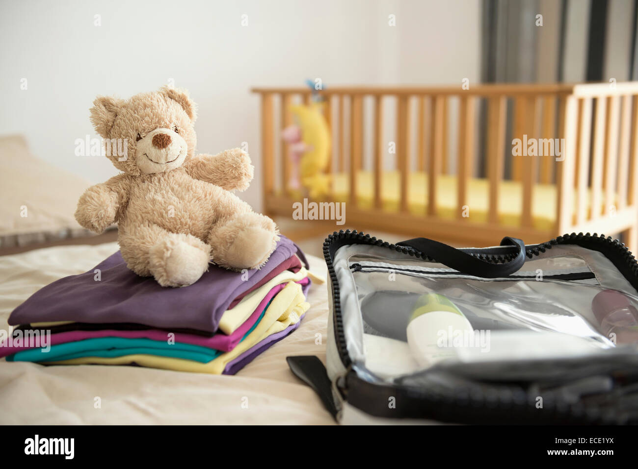 Baby bedroom cot teddy bear clothes suitcase Stock Photo