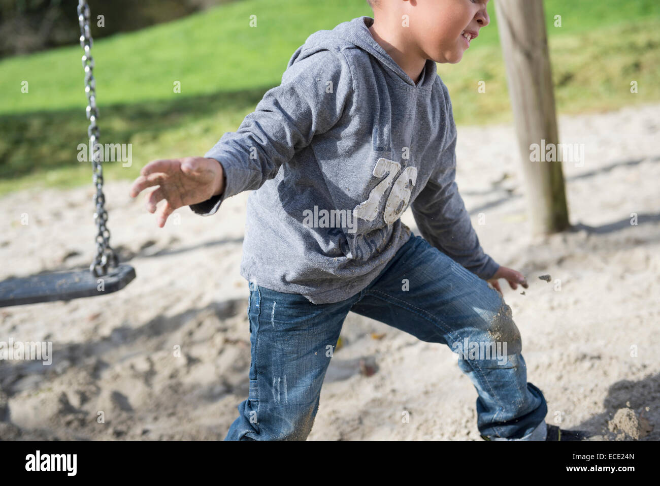 Boy playing swing playground sand action Stock Photo