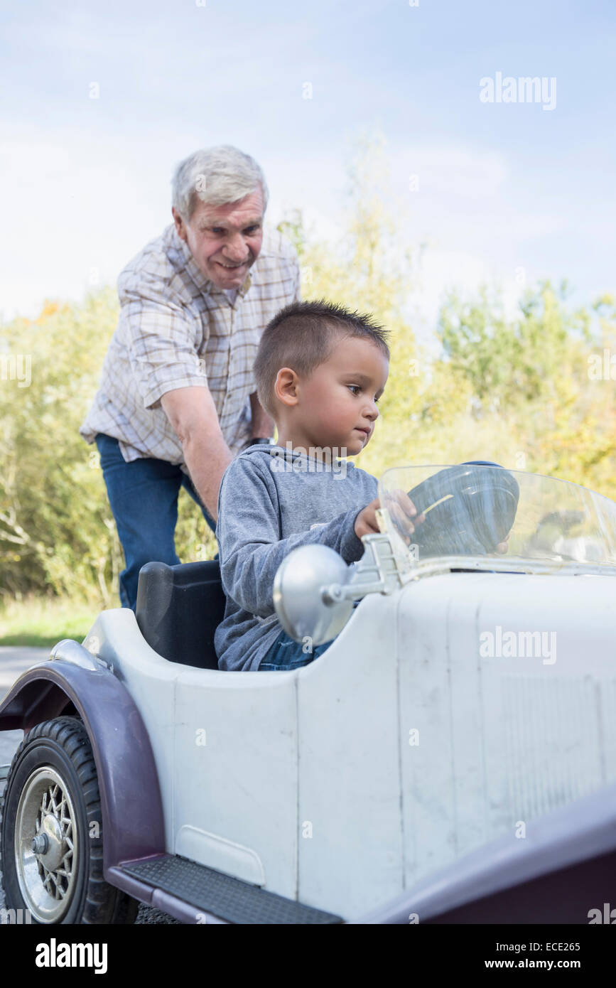 Grandson driving vintage model car grandfather Stock Photo