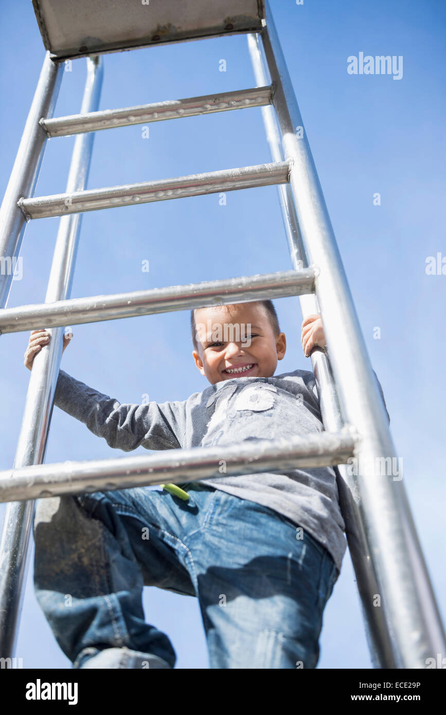 Boy smiling climbing slide ladder playground Stock Photo