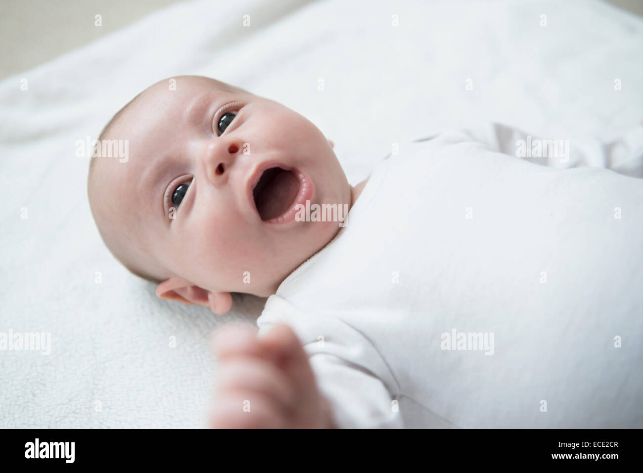 Baby boy lying on bed with mouth open Stock Photo
