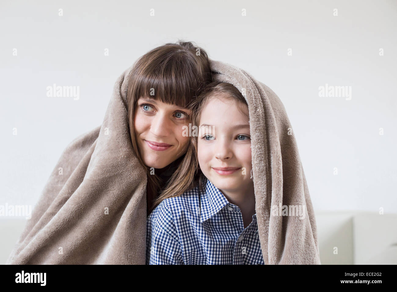Mother and daughter covered with blanket, smiling Stock Photo Alamy