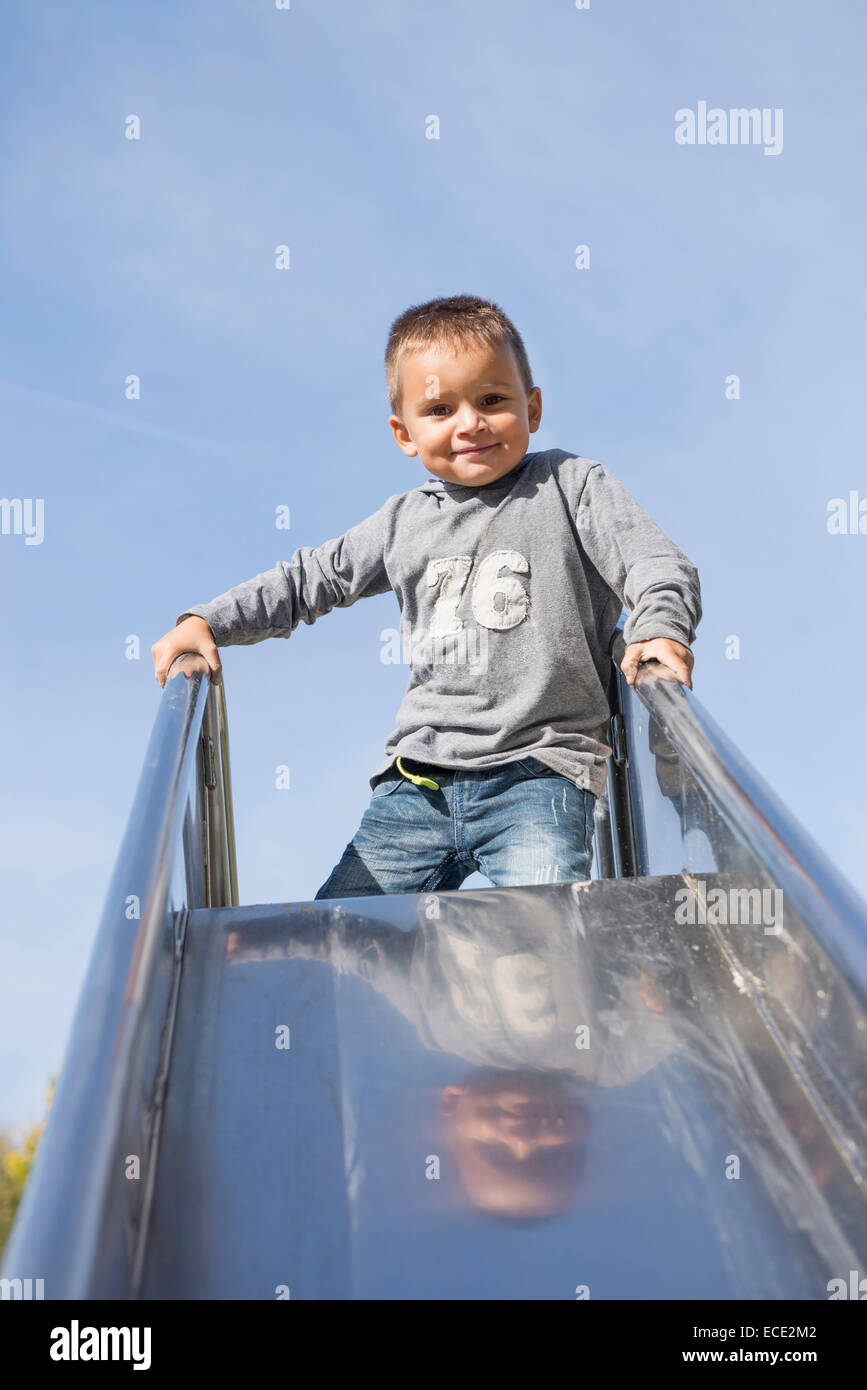 Boy young playground slide kneeling sliding Stock Photo