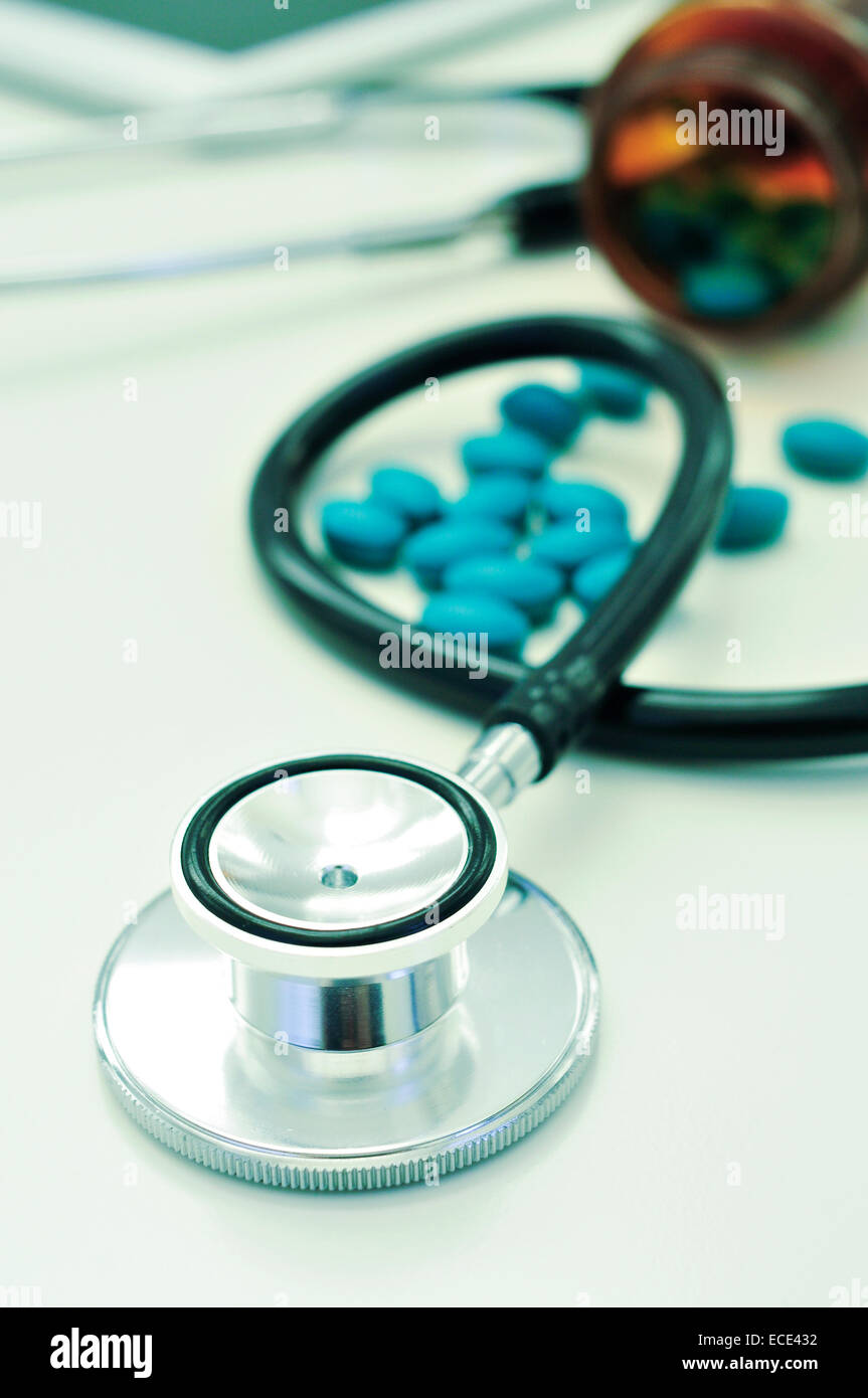 closeup of the desk of a doctors office with a stethoscope and a bottle with pills Stock Photo