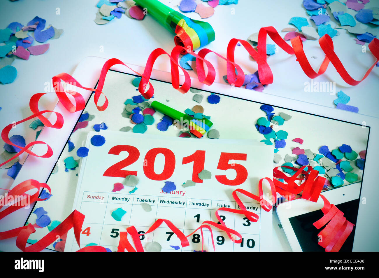 a tablet with a picture of a 2015 calendar on an office desk full of confetti, streamers and a party horn, on an office desk ful Stock Photo