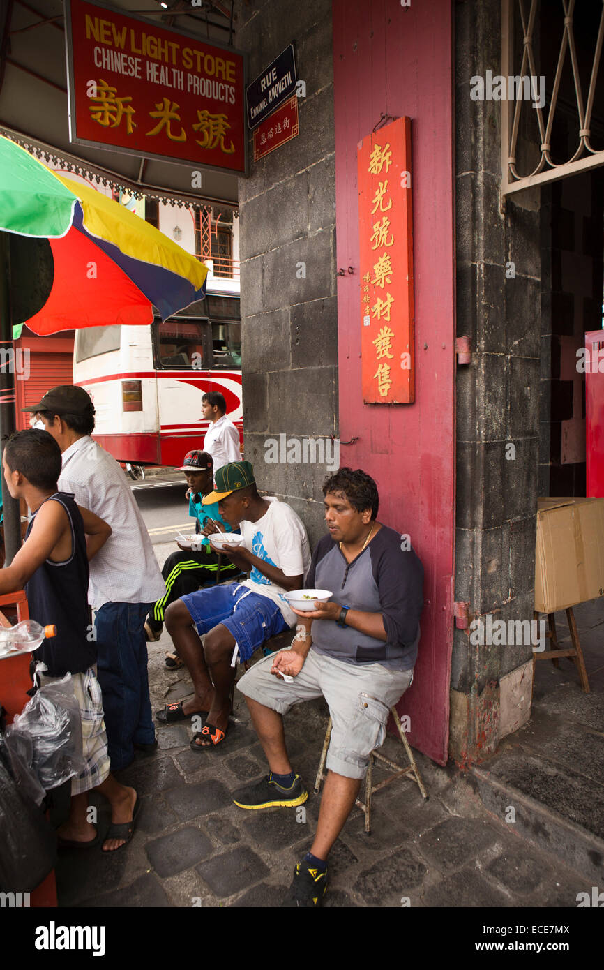 Mauritius, Port Louis, Rue Emmanual Anquetil, Chinatown, men eating Chinese fast food from pavement noodle stall Stock Photo