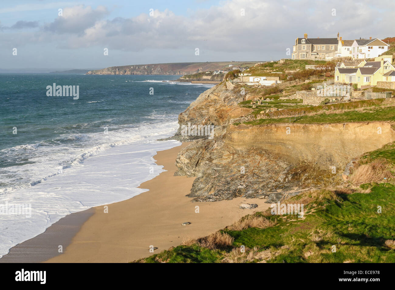 Loe Bar, Porthleven with waves breaking on a sandy beach on a sunny December day.  Overlooked by holiday cottages. Stock Photo