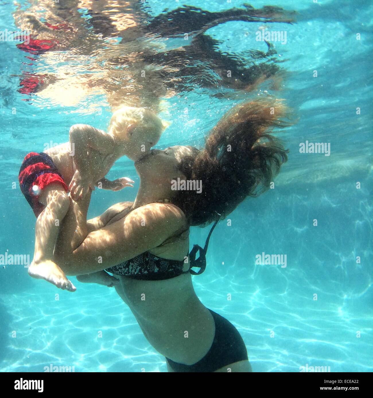 Mother kissing baby boy underwater in a swimming pool Stock Photo