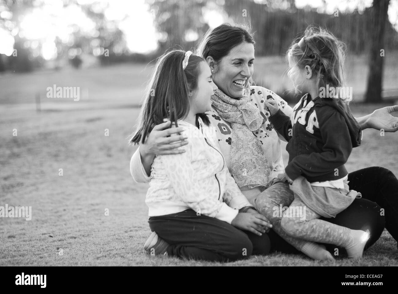 Mother sitting in the park with her two daughters, Buenos Aires, Argentina Stock Photo
