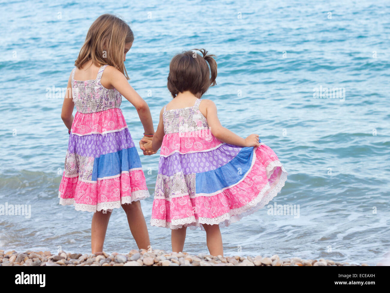 Two sisters standing on beach holding hands Stock Photo
