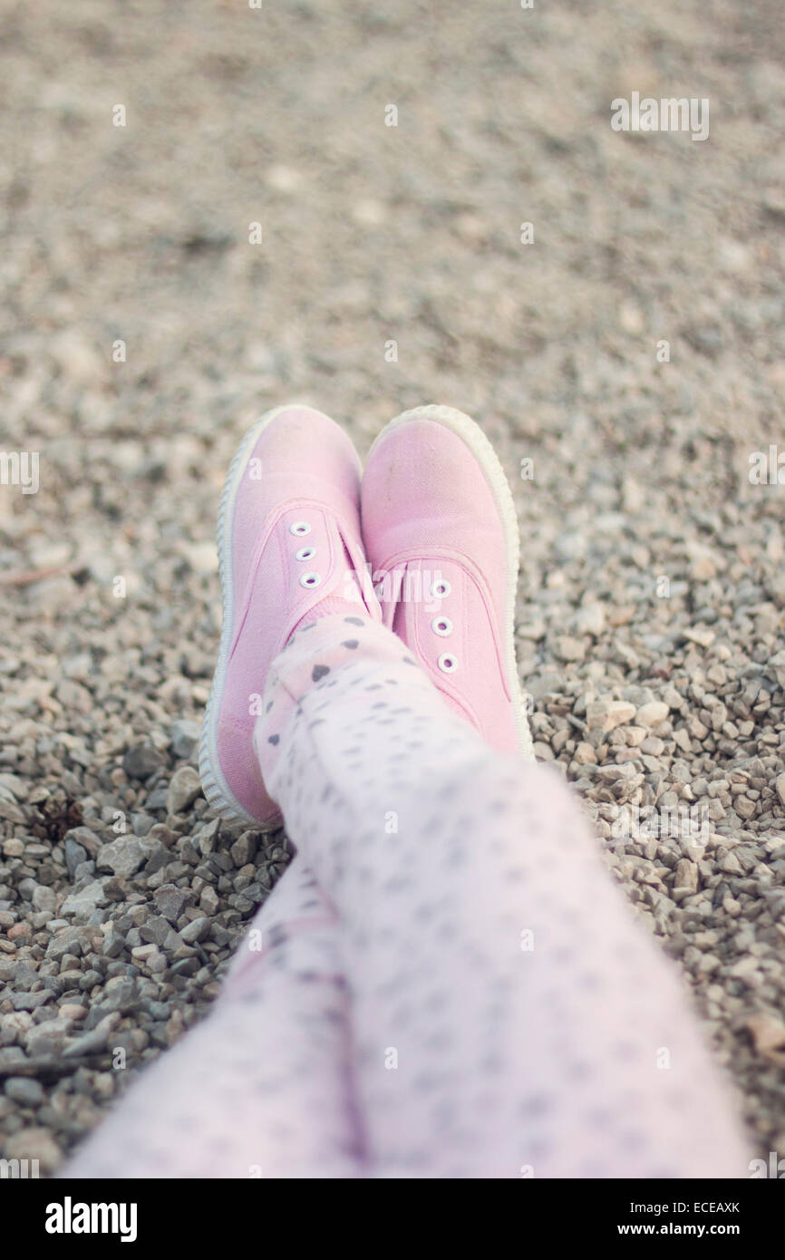 Legs in pink sneakers on sand Stock Photo