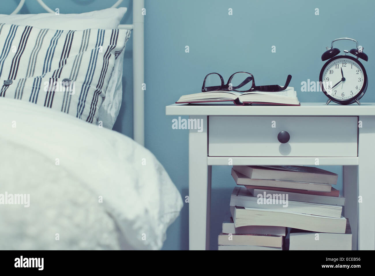 Night table with books and alarm clock Stock Photo