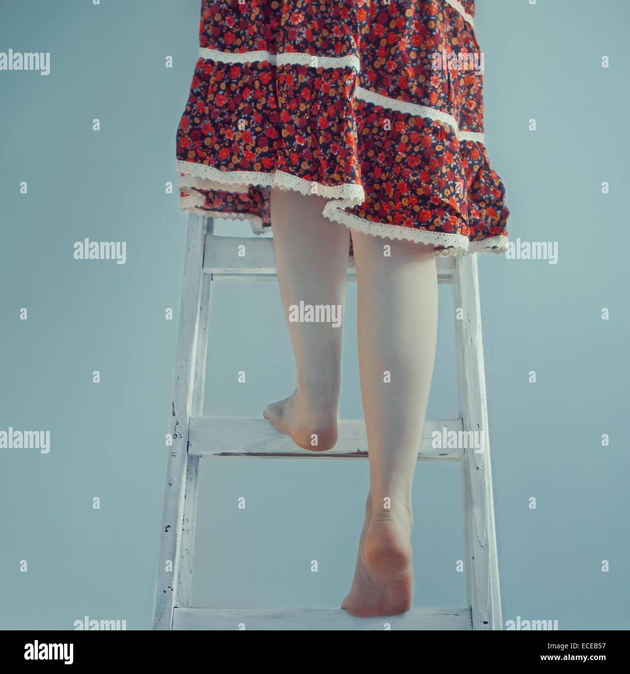 Woman climbing up a ladder Stock Photo