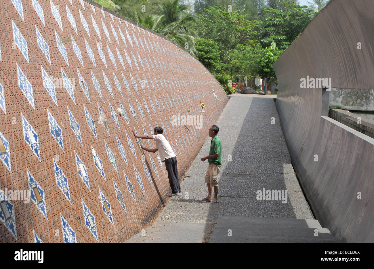 Workers clean the tsunami monument before the 10th anniversary of the tsunami, which happened during Christmas 2004, in Ban Nam Khem, Thailand, 20 November 2014. Relatives have placed tiles there in memory of their loved ones. More than 8,000 people were killed in the region. Photo: CHRISTAINE OELRICH/dpa Stock Photo