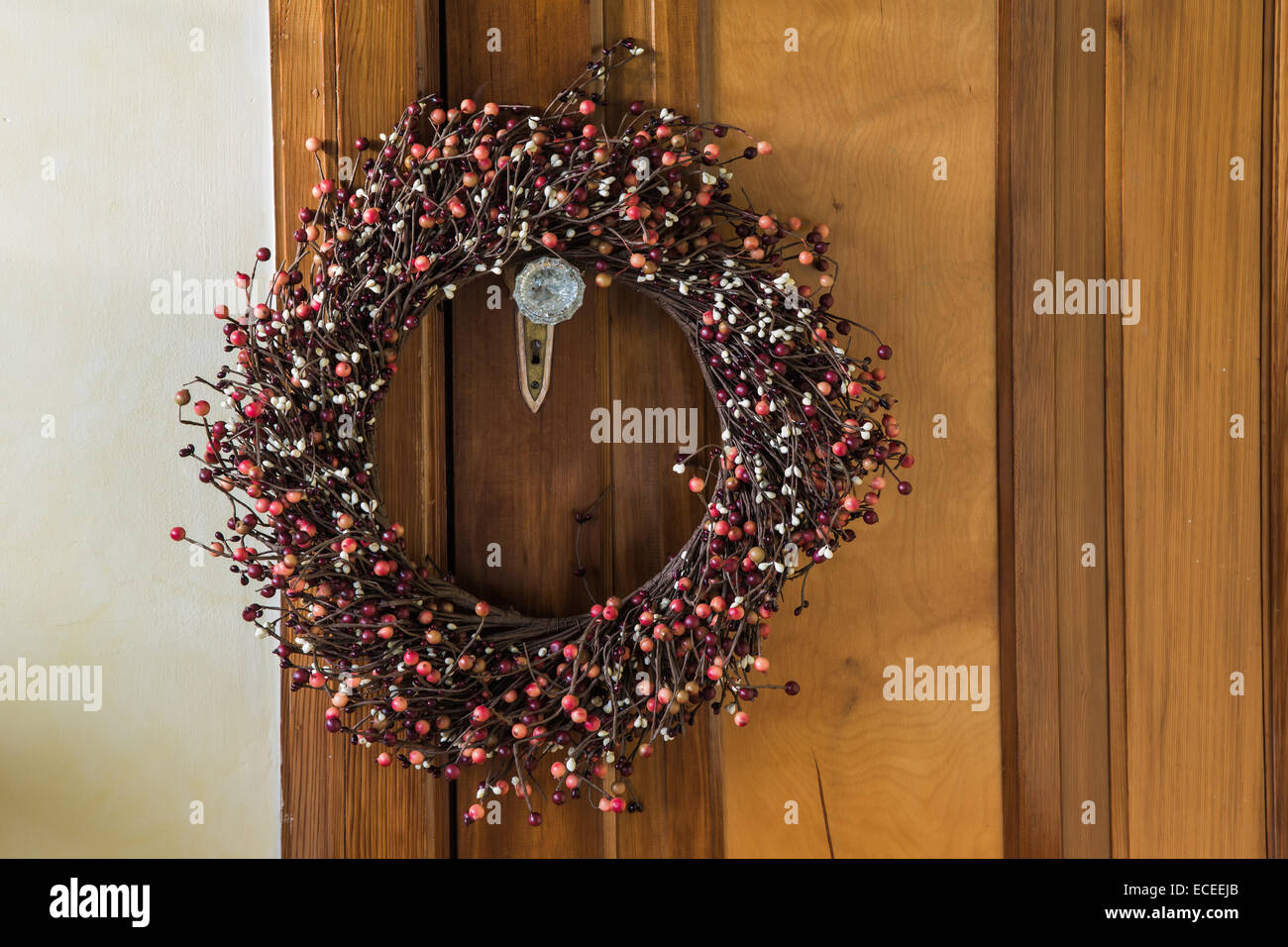 Rustic berry Christmas wreath hanging on a vintage door. Stock Photo